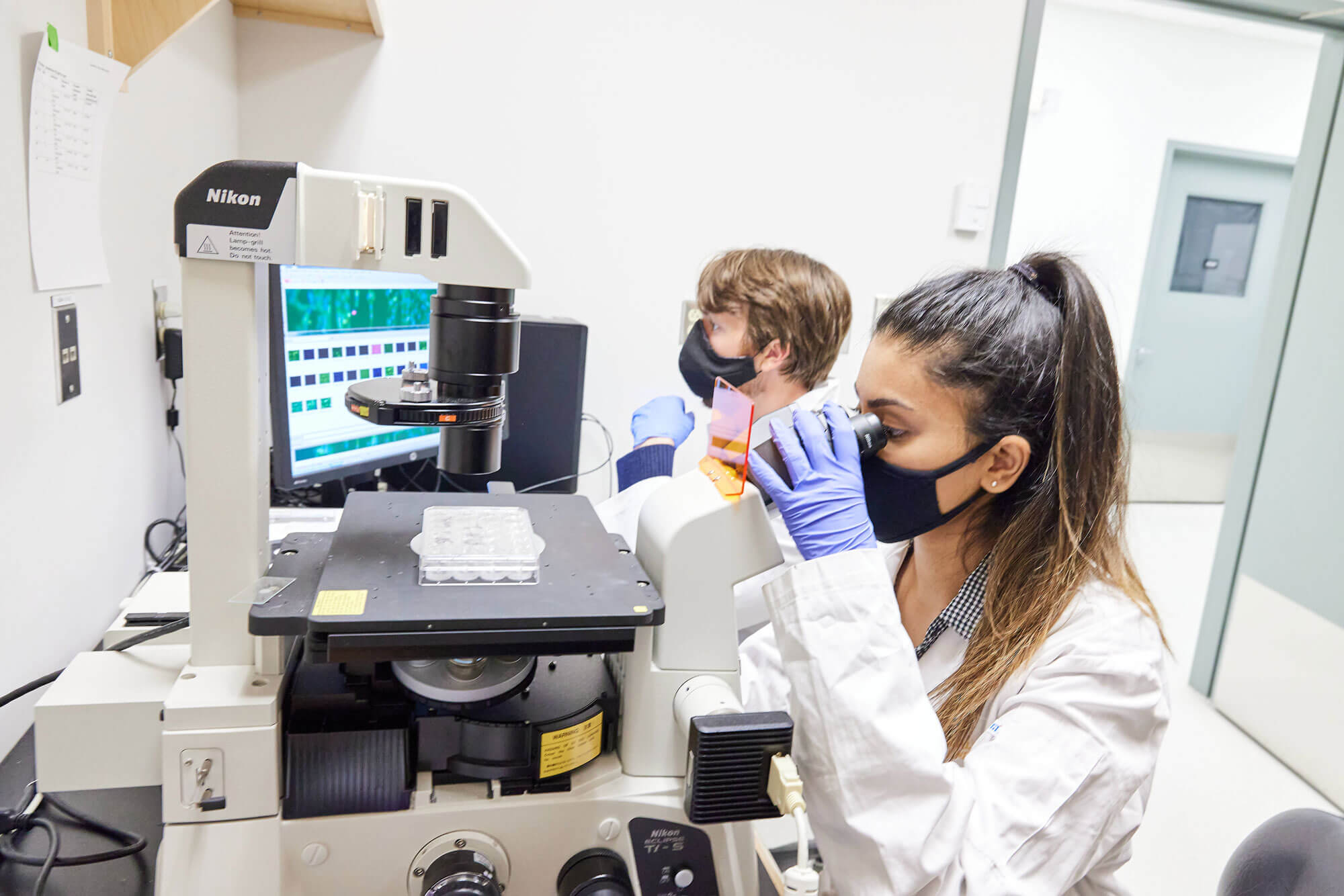 Image of engineer looking through microscope in the 3d biofibr lab